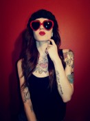 Woman with heart sunglasses, tattoos, long hair