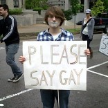 Student holding "please say gay" sign.