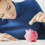 woman-putting-money-into-a-piggy-bank